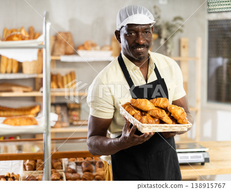 Male baker holding a tray of freshly baked croissants Male baker holding a tray of freshly baked croissants 138915767