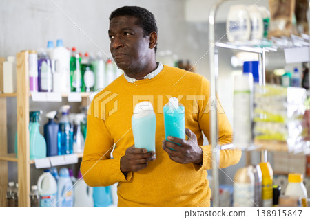 Male buyer chooses shampoo or shower gel in household goods department of supermarket Male buyer chooses shampoo or shower gel in household goods department of supermarket 138915847