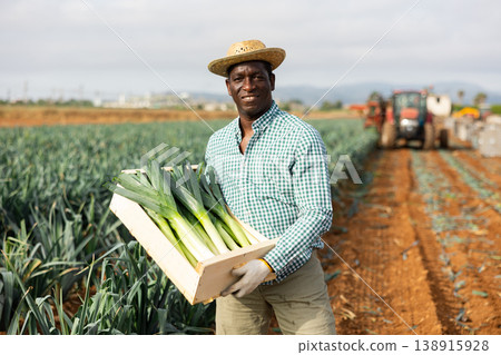 Successful african american horticulturist showing harested leek in box 138915928