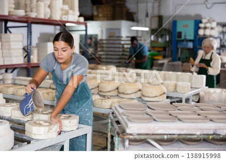 Pouring slip mass into plaster molds at pottery factory Pouring slip mass into plaster molds at pottery factory 138915998