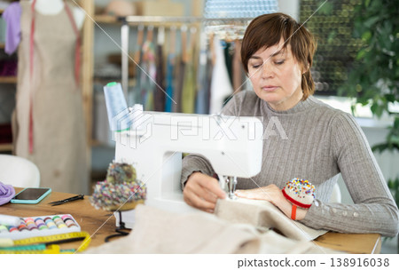 Female seamstress working on sewing machine in workshop Female seamstress working on sewing machine in workshop 138916038