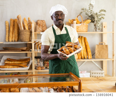 Male baker holding a tray of freshly baked croissants Male baker holding a tray of freshly baked croissants 138916041