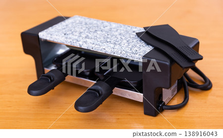 Table-top grill involved in serving swiss dish of raclette 138916043