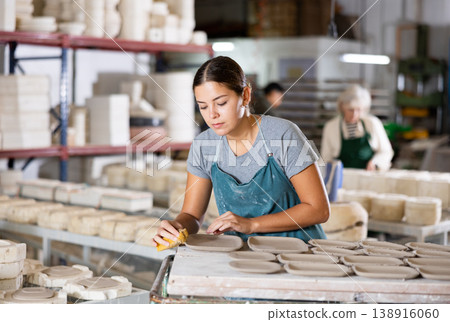 Woman potter polishing new crafted plates Woman potter polishing new crafted plates 138916060