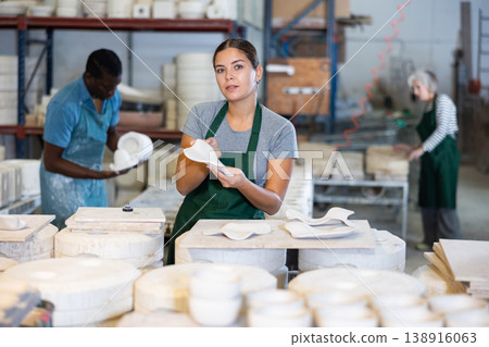 Happy female sculptor checks quality of designer clay plates 138916063