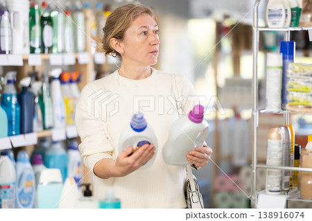 Adult woman buyer chooses detergent in store Adult woman buyer chooses detergent in store 138916074