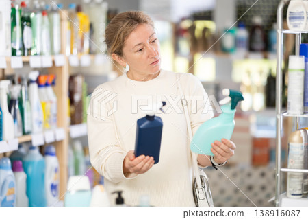 Adult woman chooses cleaning spray in store Adult woman chooses cleaning spray in store 138916087