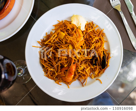 Plate of appetizing pasta noodles, seafood shrimps, mussels and sauce served on the glass table in a cafe 138916098