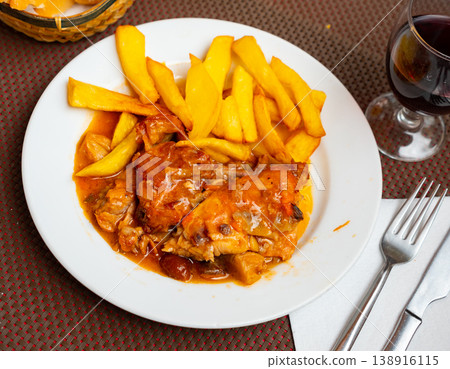 Stewed rabbit pieces served with side dish of fries Stewed rabbit pieces served with side dish of fries 138916115