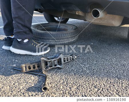 A young man takes out a spare tire from under the trunk of a car to replace a damaged tire. High quality photo A young man takes out a spare tire from under the trunk of a car to replace a damaged tire. High quality photo 138916198