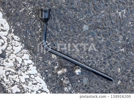 A wrench for loosening the bolts on a car wheel to remove the wheel and replace it with the spare. The process of replacing a car wheel. High quality photo A wrench for loosening the bolts on a car wheel to remove the wheel and replace it with the spare. The process of replacing a car wheel. High quality photo 138916200