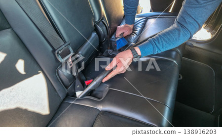 A young man vacuums and cleans the interior of a car. Car cleaning and detailing. High quality photo A young man vacuums and cleans the interior of a car. Car cleaning and detailing. High quality photo 138916203