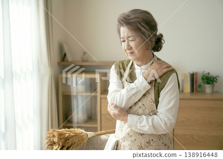 一位日本老年婦女因肩痛而面露痛苦之色；圖片顯示的是肩周炎或肌肉疼痛。生成式人工智慧 138916448