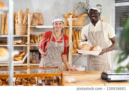Portrait of two bakery employees - man and woman showing delicious baguettes and croissants Portrait of two bakery employees - man and woman showing delicious baguettes and croissants 138916681