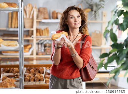 Joyful woman holding fresh bocadillo in bakery Joyful woman holding fresh bocadillo in bakery 138916685