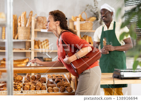 Woman in casual clothes chooses hot croissants for breakfast in bakery Woman in casual clothes chooses hot croissants for breakfast in bakery 138916694