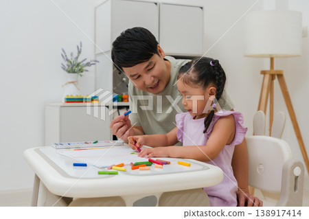 Caption/Description: father and child girl drawing and painting with colorful oil pastels on paper Caption/Description: father and child girl drawing and painting with colorful oil pastels on paper 138917414