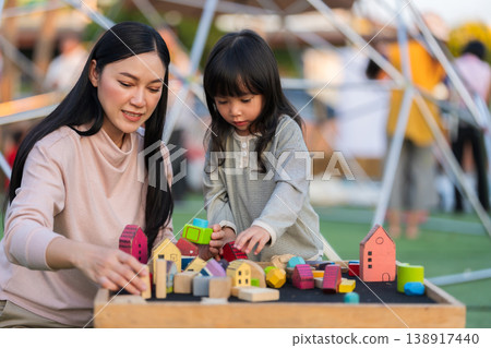 mother and preschool child girl playing with wooden toy block at outdoor 138917440