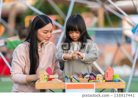 mother and preschool child girl playing with wooden toy block at outdoor 138917441