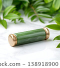 Elegant jade roller on a marble surface surrounded by lush green foliage and natural elements 138918900