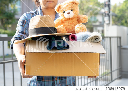 Volunteer woman holding clothing and doll donation box. 138918979