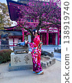 一位身穿和服的人在神社的梅樹下撫摸著一尊牛雕像。 138919740