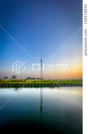 A Tranquil Reflection of a Communication Tower at Sunset, Bathing the Scene in Orange and Blue 138919930