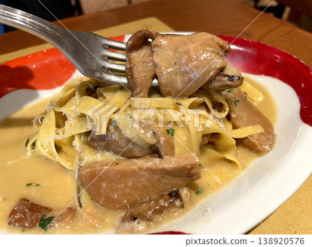 Tagliatelle with porcini mushrooms - close-up of a porcini mushroom picked up with a fork. 138920576