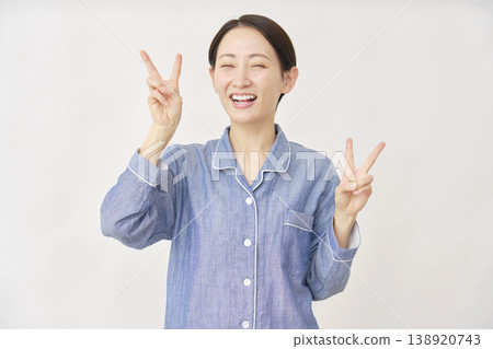 身穿睡衣的女子雙手放在白色背景上做出“和平手勢” 138920743