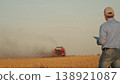 farmer working in wheat field, combine harvester ploughing in wheat field, agriculture tablet, digital tools for farmers, agricultural business strategies, field management via tablet, enhancing 138921087