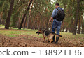Hiking with dog, sunny forest, casual clothes, natural landscape, healthy lifestyle, animal companion, German Shepherd smiling, dirt trail, woodland stroll, serene surroundings. Outdoor activity, man 138921136