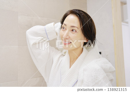 A woman wiping her wet hair with a bath towel after taking a bath A woman wiping her wet hair with a bath towel after taking a bath 138921315