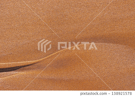 Rhythmic sand ripples create a hypnotic geometric pattern. Parallel lines and soft shadows enhance the tactile organic texture of this minimalist desert landscape view 138921578