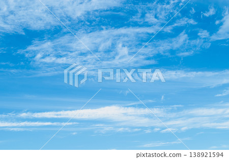 Panoramic view of a clear azure sky with wispy cirrus clouds. Soft blue gradients and airy textures create a vast minimalist backdrop with extensive copy space for web 138921594
