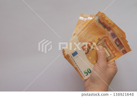 Female hands holding a large fan of 50 Euro banknotes against a white background. High-volume cash concept with orange bills and extensive copy space for design Female hands holding a large fan of 50 Euro banknotes against a white background. High-volume cash concept with orange bills and extensive copy space for design 138921648