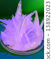 Close up view of sharp, translucent crystals forming in a petri dish under purple and green lighting, showcasing a scientific experiment 138922023