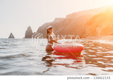 Woman, ocean, donut. Young woman enjoys summer vacation floating with a pink donut inflatable. Woman, ocean, donut. Young woman enjoys summer vacation floating with a pink donut inflatable. 138922133