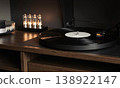 Turntable vinyl record vacuum tube amplifier on a wooden console creates a warm and moody atmosphere for an audiophile 138922147