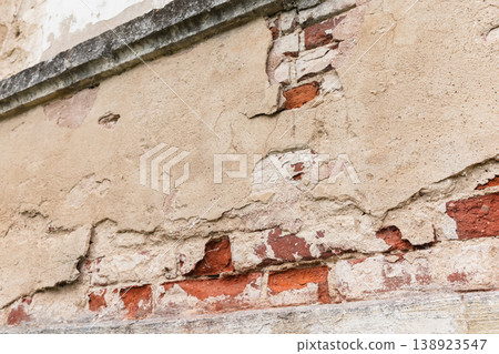 Old peeling plaster reveals weathered red brick and cracked stucco Old peeling plaster reveals weathered red brick and cracked stucco 138923547