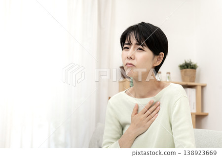 A woman clutches her chest, suddenly feeling unwell; chest pain, stress. A woman clutches her chest, suddenly feeling unwell; chest pain, stress. 138923669