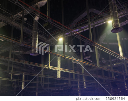 Industrial ceiling with complex metallic ventilation ducts, pipes, and conduits illuminated by spotlights, symbolizing advanced engineering and modern infrastructure Industrial ceiling with complex metallic ventilation ducts, pipes, and conduits illuminated by spotlights, symbolizing advanced engineering and modern infrastructure 138924564