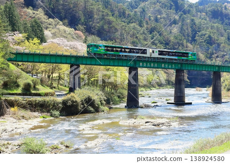 The Suigun Line's "Kazekko Suigun" train runs against a backdrop of fresh greenery and mountain cherry blossoms. 138924580