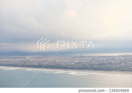 Aerial view of a seaside town and distant mountain ranges. Aerial view of a seaside town and distant mountain ranges. 138924669
