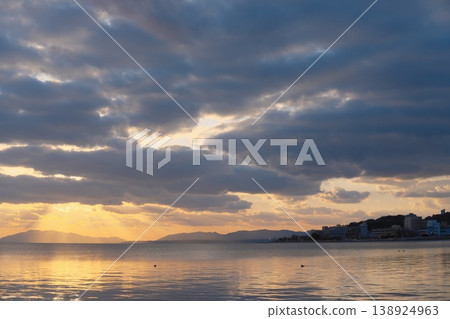 The calm surface of the lake at dusk, the distant mountain range, and the clouds floating in the sky. The calm surface of the lake at dusk, the distant mountain range, and the clouds floating in the sky. 138924963