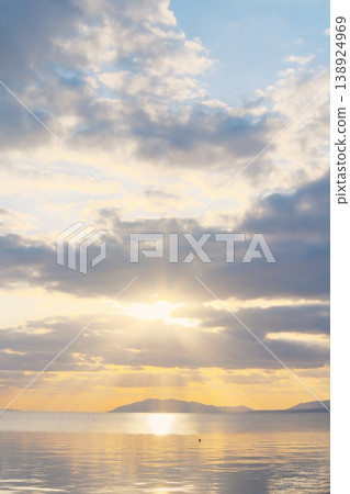 黃昏時分平靜的湖面，遠處綿延的山脈，以及天空中飄浮的雲朵。 138924969