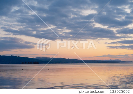 The tranquility of Lake Shinji at dusk, the sun setting on the horizon and the calm lake. 138925002