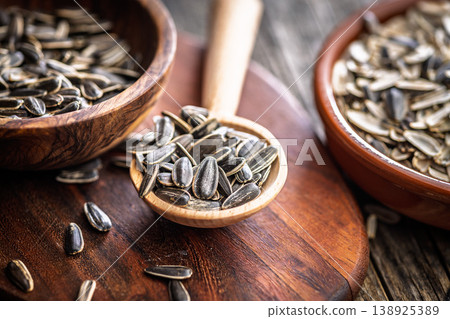 Sunflower Seeds in Wooden Spoon With Bowls on Rustic Cutting Board, Close-Up Texture Sunflower Seeds in Wooden Spoon With Bowls on Rustic Cutting Board, Close-Up Texture 138925389