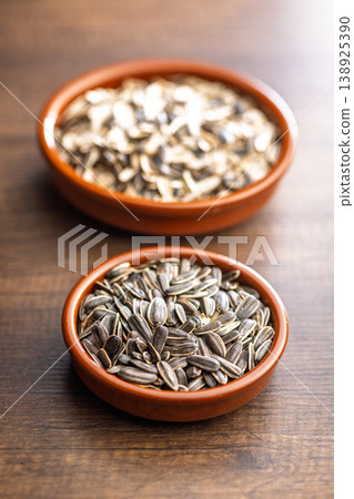 Sunflower Seeds in Ceramic Bowls on Wooden Table. Raw Snack and Healthy Ingredient Close-Up Sunflower Seeds in Ceramic Bowls on Wooden Table. Raw Snack and Healthy Ingredient Close-Up 138925390