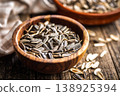 Sunflower Seeds in Bowl on Wooden Table With Scattered Shells Rustic Snack Background 138925394