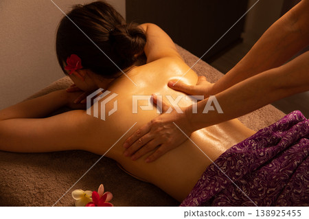 A woman receiving a back massage at a Balinese spa. A woman receiving a back massage at a Balinese spa. 138925455